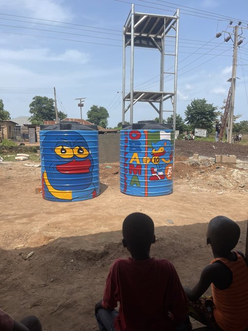 Two water tanks on a tower painted with Sproto Gremlins, Onipanu village